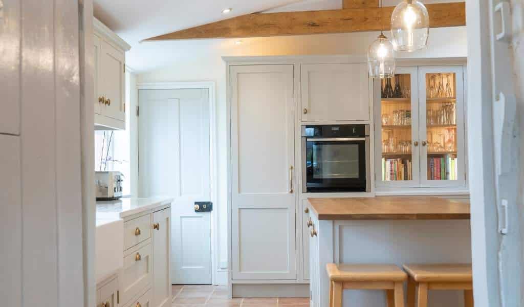 Modern kitchen with wooden countertops, glass pendant lights, an oven, and white cabinets.
