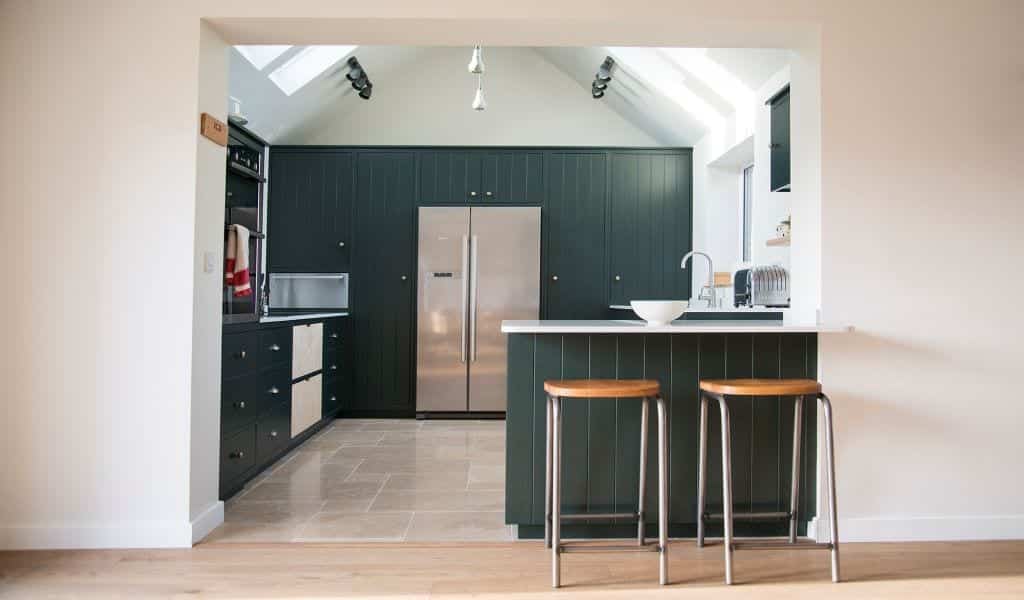 Modern kitchen with dark cabinets, stainless appliances, and a breakfast bar with two stools.