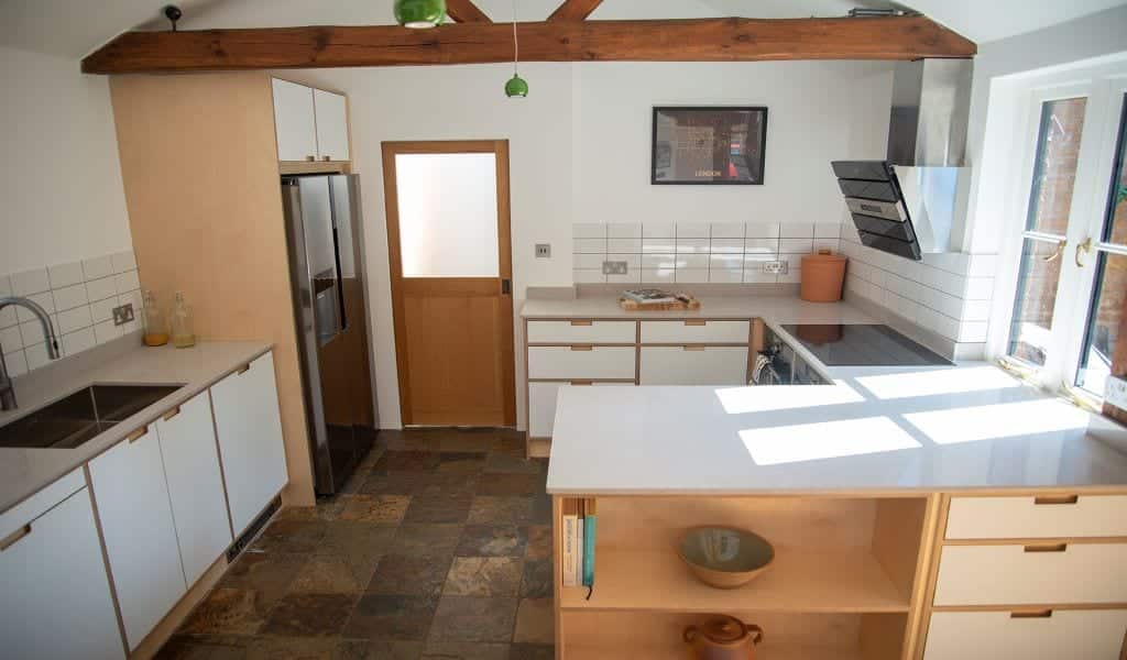 Spacious kitchen with white cabinets, wooden beams, and ample natural light.