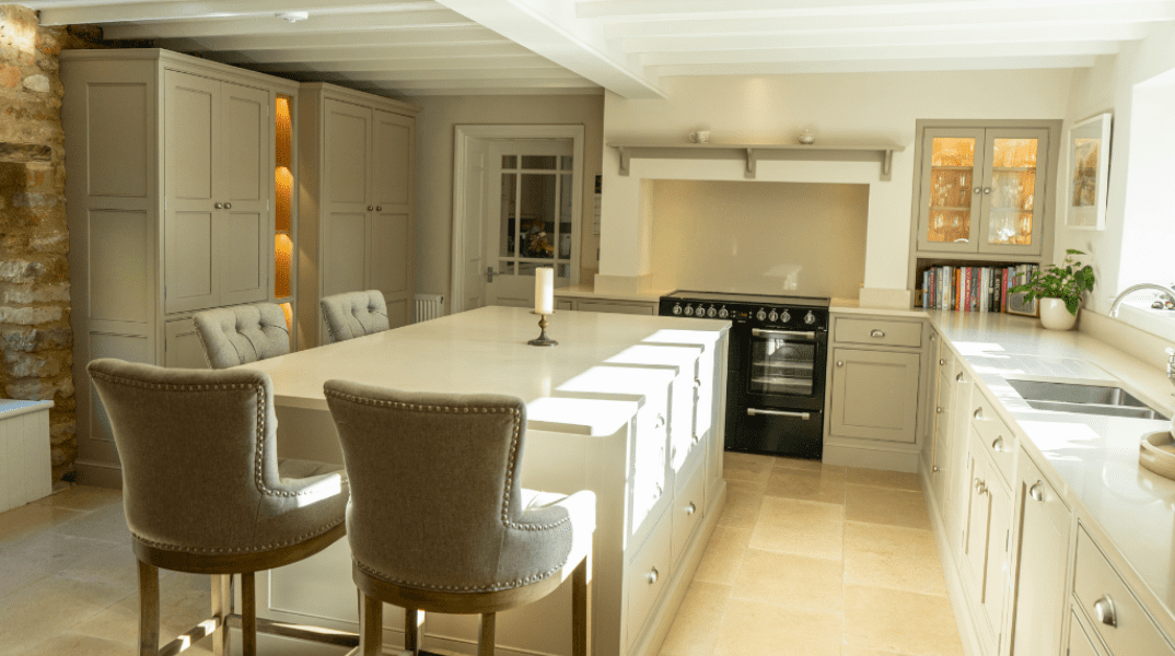 Bright kitchen with an island, two chairs, and modern appliances under exposed beams.