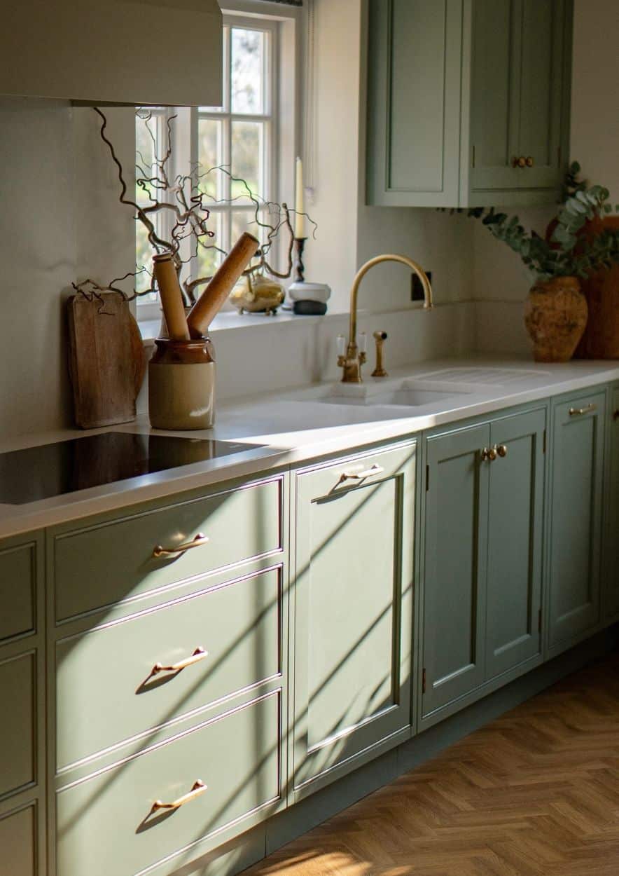Bright kitchen with wooden floors, white cabinets, and a window above the sink.