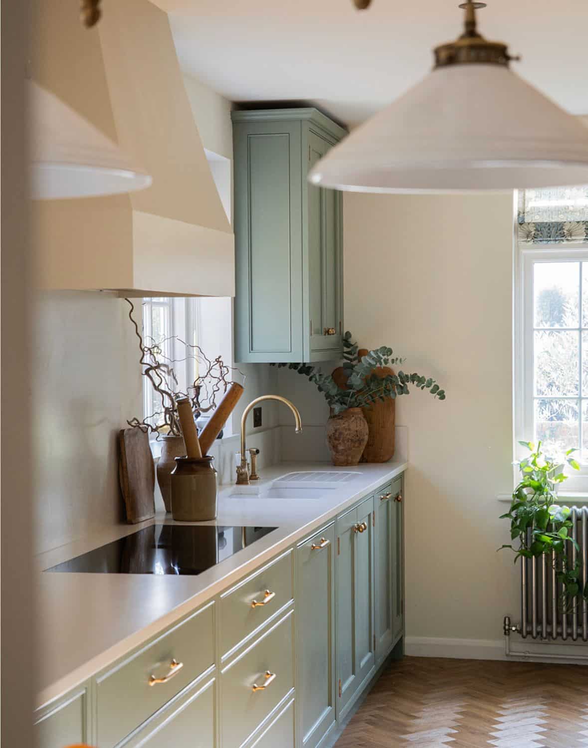 Bright kitchen with an island, wicker chairs, wood floor, and large windows letting in natural light.
